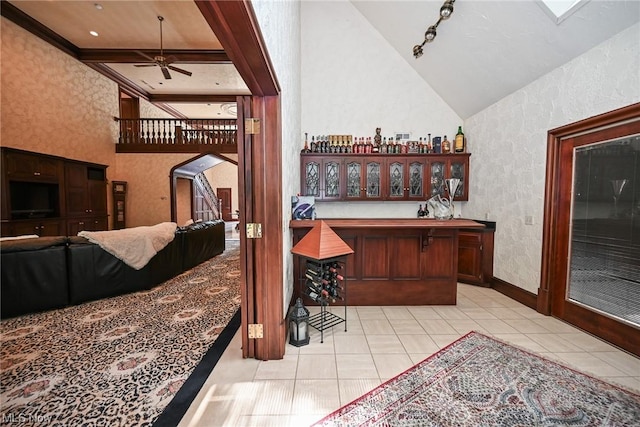 bar with light tile patterned floors, ceiling fan, and a high ceiling