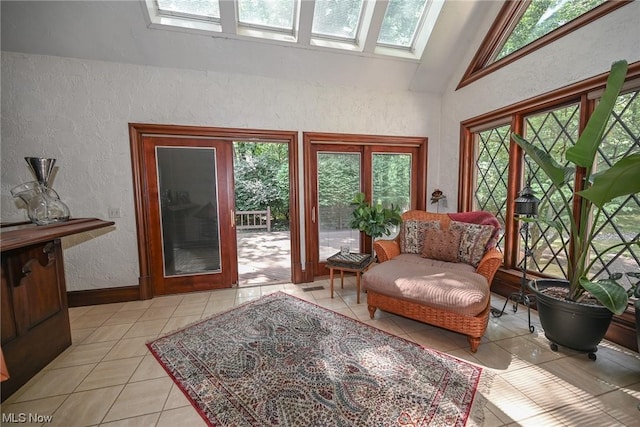 living area with vaulted ceiling with skylight and light tile patterned flooring