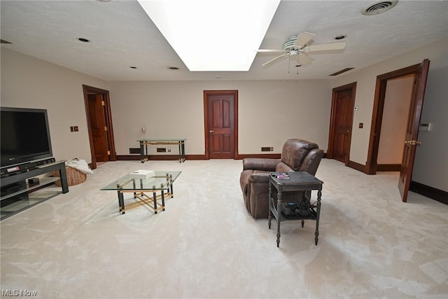 living room with ceiling fan, light colored carpet, and a skylight