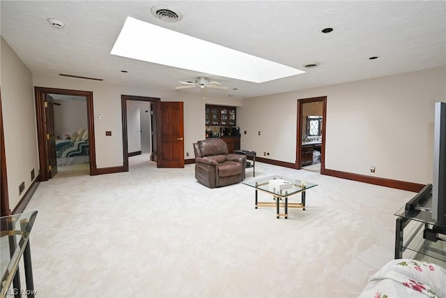 carpeted living room featuring a skylight and ceiling fan