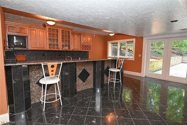 bar featuring decorative backsplash, a textured ceiling, and black microwave