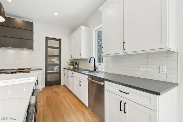 kitchen with backsplash, sink, white cabinetry, light hardwood / wood-style flooring, and stainless steel appliances