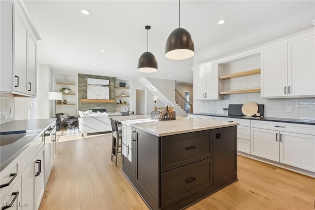 kitchen featuring decorative light fixtures, white cabinets, and a stone fireplace