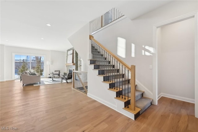 stairway with a fireplace and hardwood / wood-style flooring