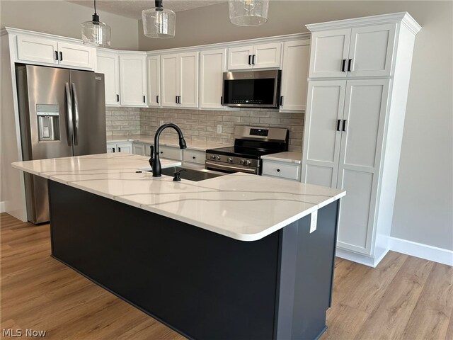 944 Queen Anne Dr NW, Massillon, OH 44647 - kitchen featuring hanging light fixtures, white cabinets, light hardwood / wood-style flooring, stainless steel appliances, and sink