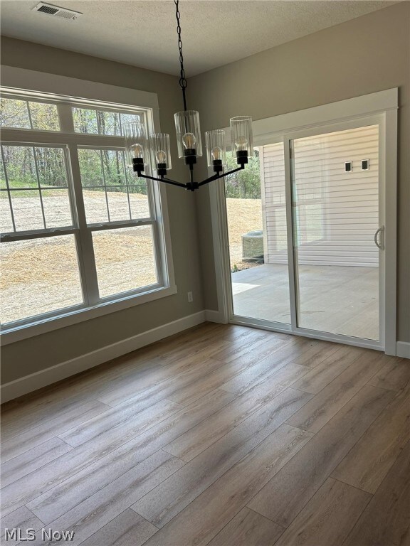 944 Queen Anne Dr NW, Massillon, OH 44647 - unfurnished dining area featuring a notable chandelier, wood-type flooring, and a wealth of natural light