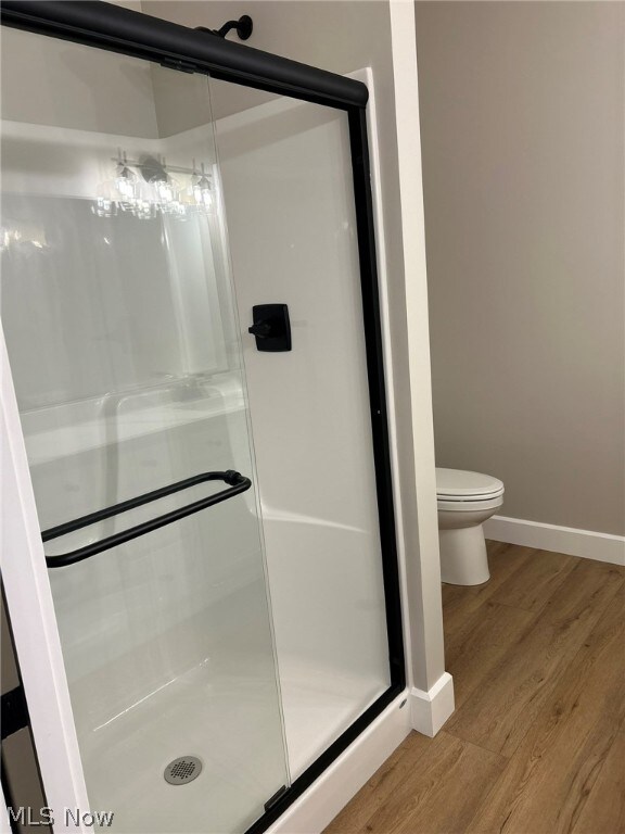 944 Queen Anne Dr NW, Massillon, OH 44647 - bathroom featuring hardwood / wood-style floors, toilet, and a shower with door