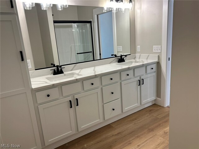 944 Queen Anne Dr NW, Massillon, OH 44647 - bathroom with hardwood / wood-style floors, double sink vanity, a chandelier, and a shower with door