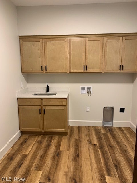 clothes washing area with cabinets, sink, hookup for a washing machine, and hardwood / wood-style flooring