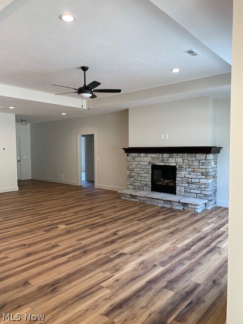 unfurnished living room with hardwood / wood-style floors, ceiling fan, and a fireplace