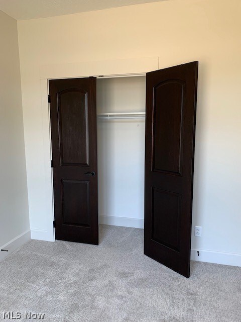 unfurnished bedroom featuring a closet and light colored carpet