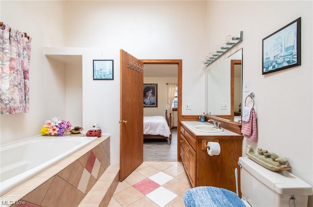 bathroom with tiled tub, tile patterned flooring, vanity, and toilet