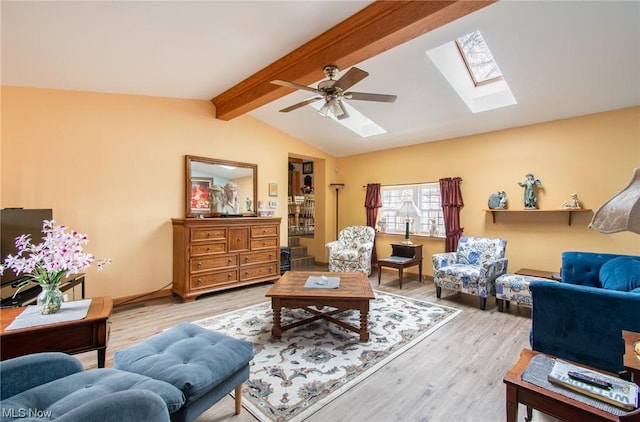 living room with vaulted ceiling with skylight, ceiling fan, and light wood-type flooring