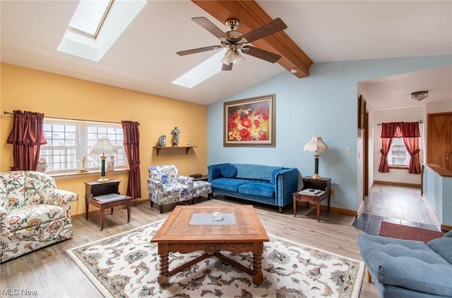 living room with ceiling fan, vaulted ceiling with skylight, and hardwood / wood-style flooring