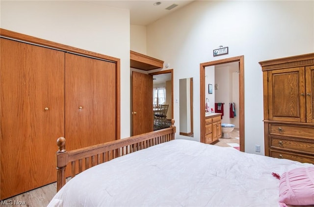 bedroom with light hardwood / wood-style flooring, connected bathroom, and a closet