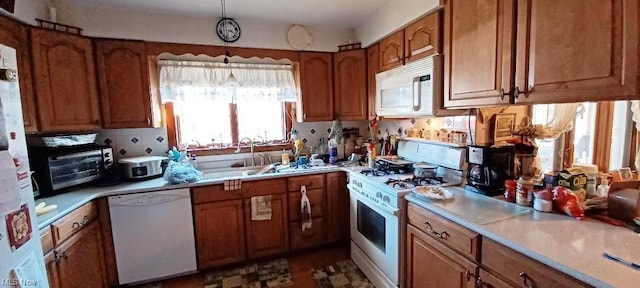 kitchen featuring hanging light fixtures, white appliances, and sink