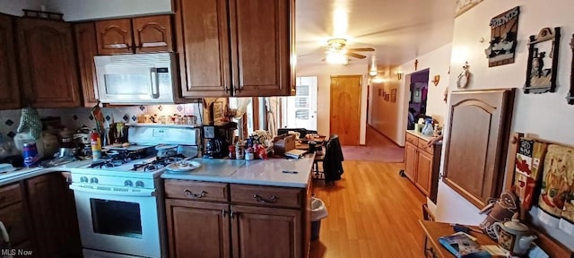 kitchen with ceiling fan, white appliances, and light hardwood / wood-style floors