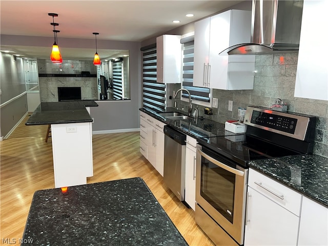 kitchen featuring appliances with stainless steel finishes, light hardwood / wood-style floors, wall chimney range hood, and white cabinetry