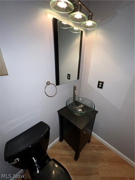 bathroom featuring hardwood / wood-style floors, a chandelier, vanity, and toilet