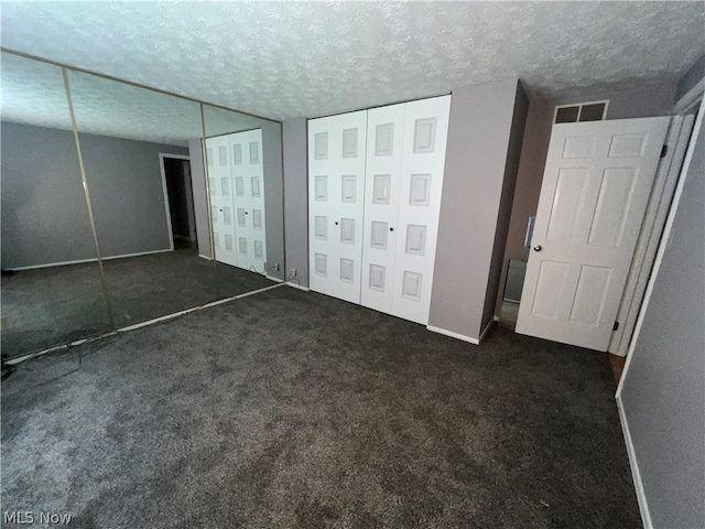 unfurnished bedroom featuring a textured ceiling and dark carpet