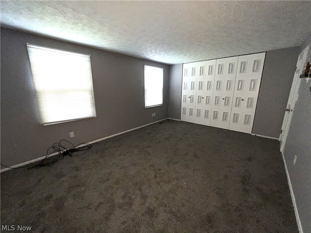 unfurnished bedroom featuring dark carpet and a textured ceiling