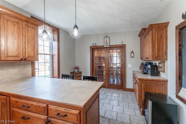 kitchen with decorative light fixtures, french doors, light tile patterned flooring, and a textured ceiling