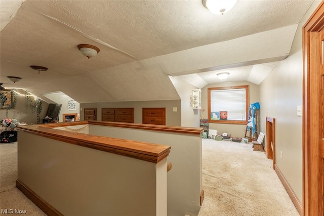 interior space featuring light carpet, a textured ceiling, and lofted ceiling