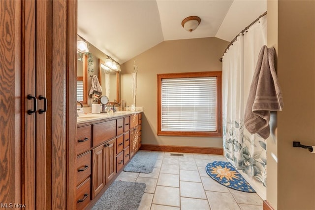 bathroom with tile patterned flooring, vanity, vaulted ceiling, and plenty of natural light