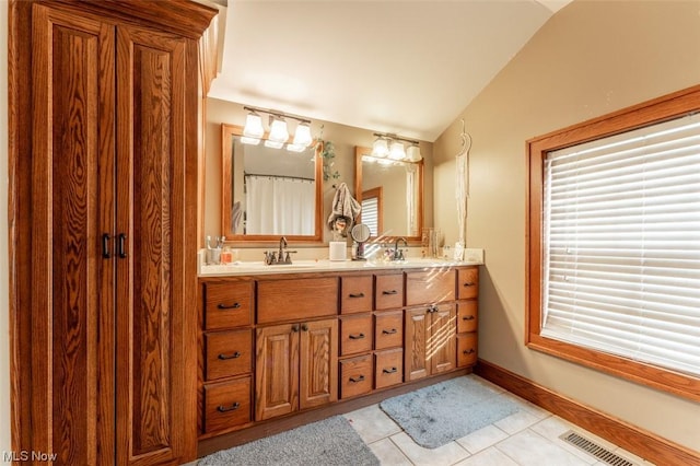 bathroom with tile patterned flooring, vanity, and vaulted ceiling