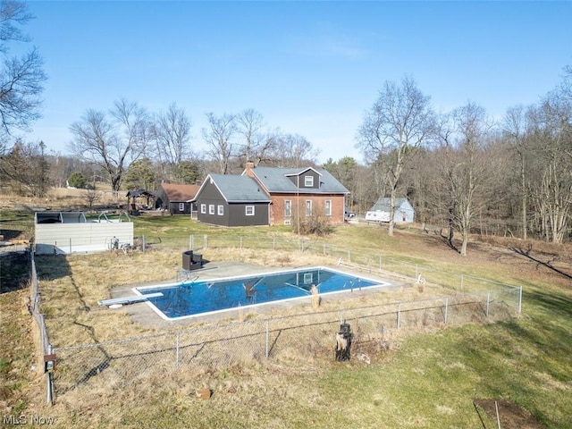 view of pool featuring a lawn and a diving board