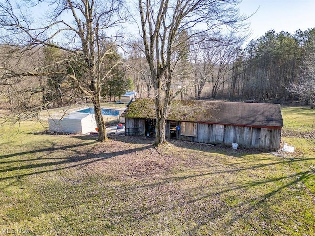 exterior space featuring a front lawn, an outbuilding, and a pool