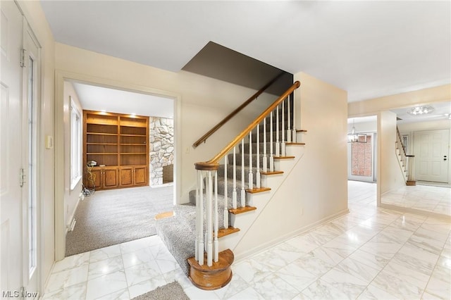 stairs with carpet flooring, a chandelier, and built in features