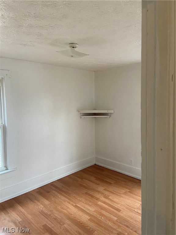 spare room with ceiling fan, light hardwood / wood-style flooring, and a textured ceiling