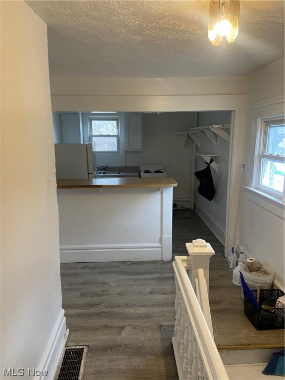 kitchen featuring a textured ceiling, a healthy amount of sunlight, a baseboard radiator, and dark wood-type flooring