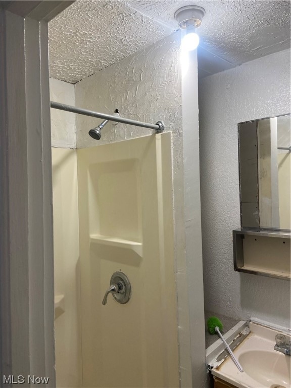 bathroom featuring a shower, sink, and a textured ceiling