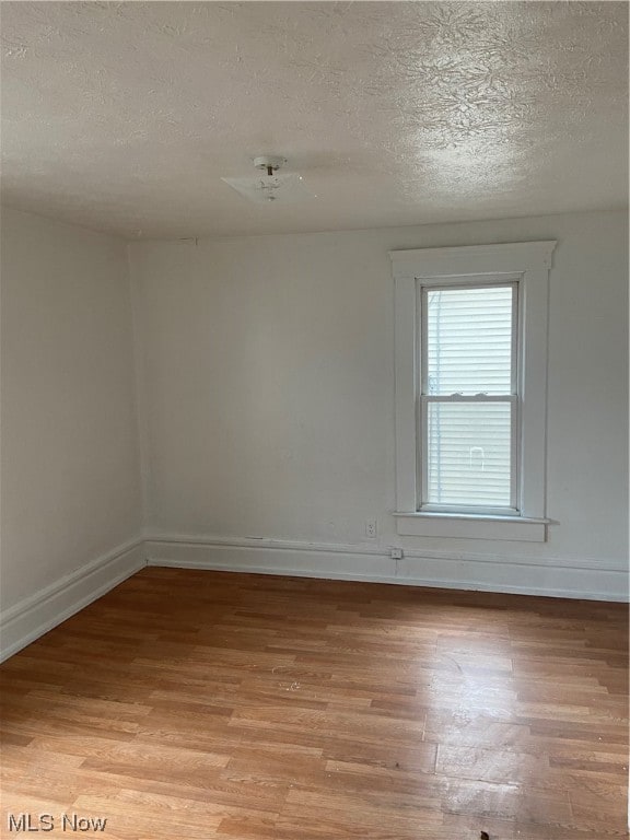 empty room featuring a textured ceiling and light hardwood / wood-style flooring