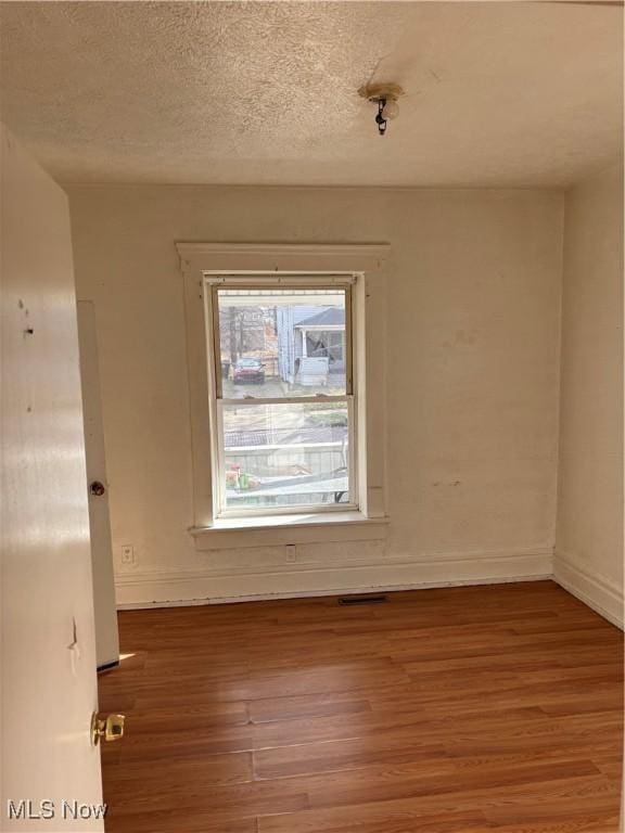 empty room with wood-type flooring and a textured ceiling