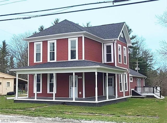 farmhouse-style home with covered porch, a shingled roof, and a front yard