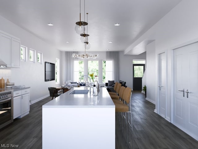 kitchen with hanging light fixtures, dark hardwood / wood-style floors, a notable chandelier, sink, and white cabinets