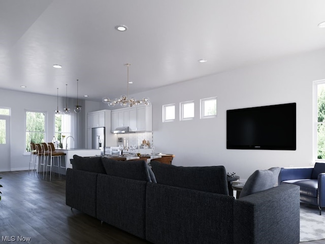 living room with plenty of natural light, a chandelier, and dark hardwood / wood-style floors