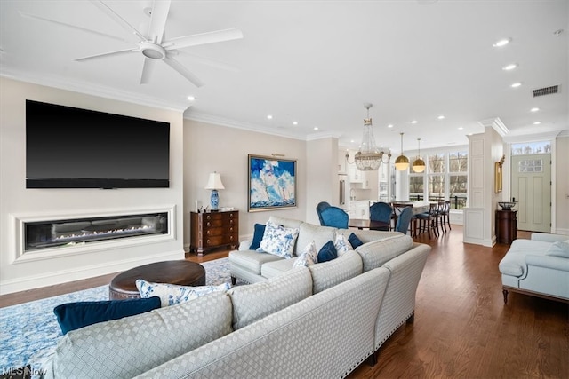 living room with crown molding, dark hardwood / wood-style flooring, and ceiling fan with notable chandelier