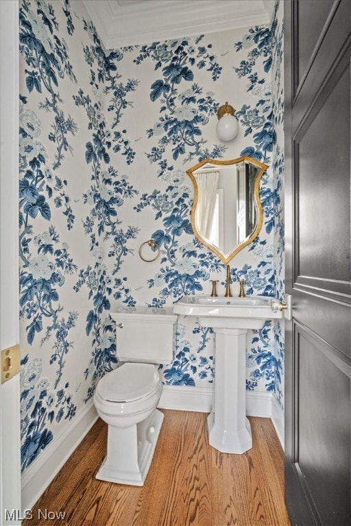 bathroom featuring toilet, ornamental molding, and wood-type flooring