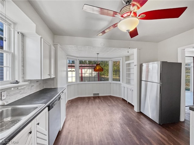 kitchen with ceiling fan, dark wood-type flooring, appliances with stainless steel finishes, white cabinets, and tasteful backsplash