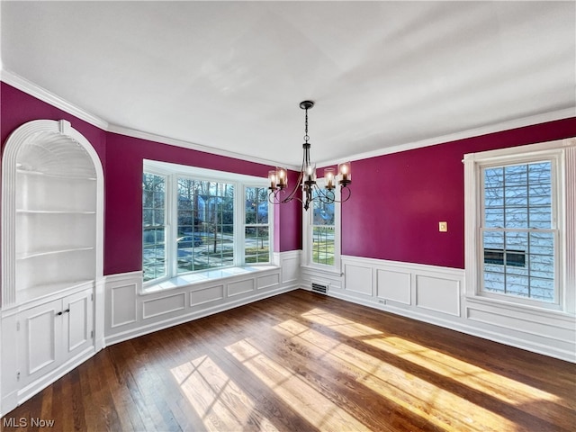 unfurnished dining area with an inviting chandelier, crown molding, and dark hardwood / wood-style floors