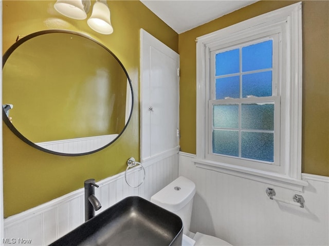 bathroom with toilet, sink, and a chandelier