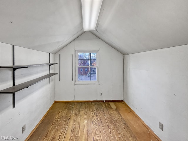 additional living space with hardwood / wood-style floors and vaulted ceiling