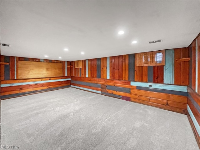 carpeted spare room with wood walls