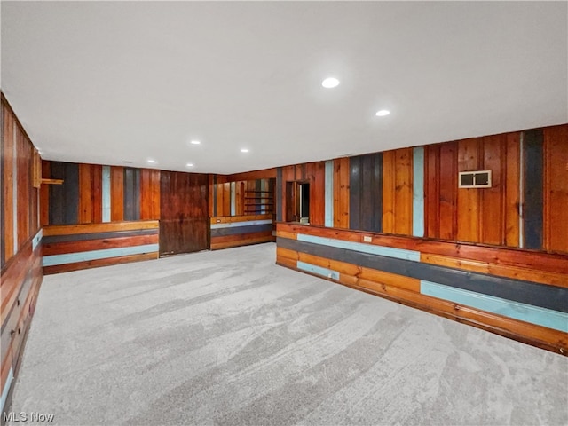 basement with wood walls and light colored carpet