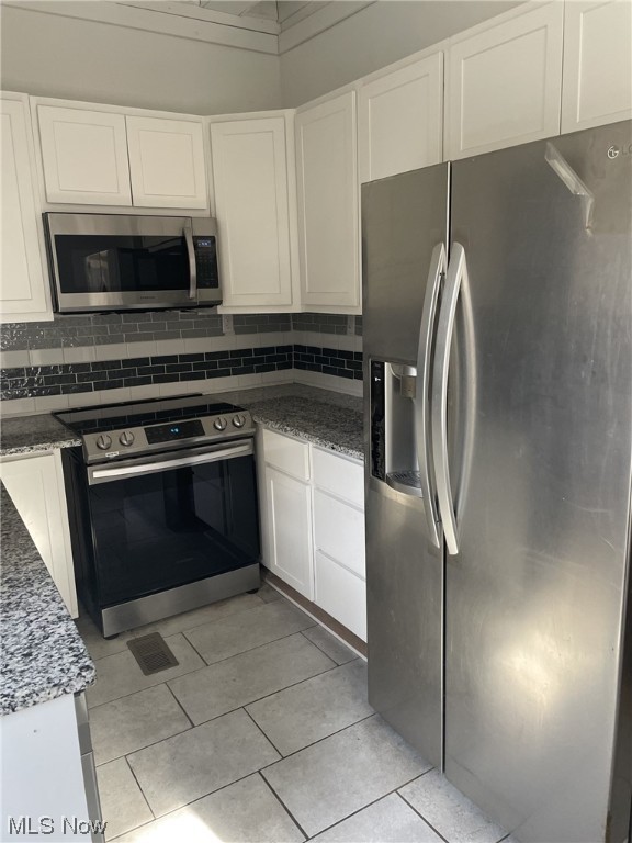 kitchen with white cabinetry, dark stone countertops, and appliances with stainless steel finishes