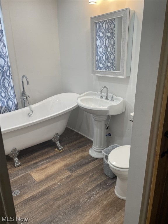 bathroom with wood-type flooring, a tub, and toilet